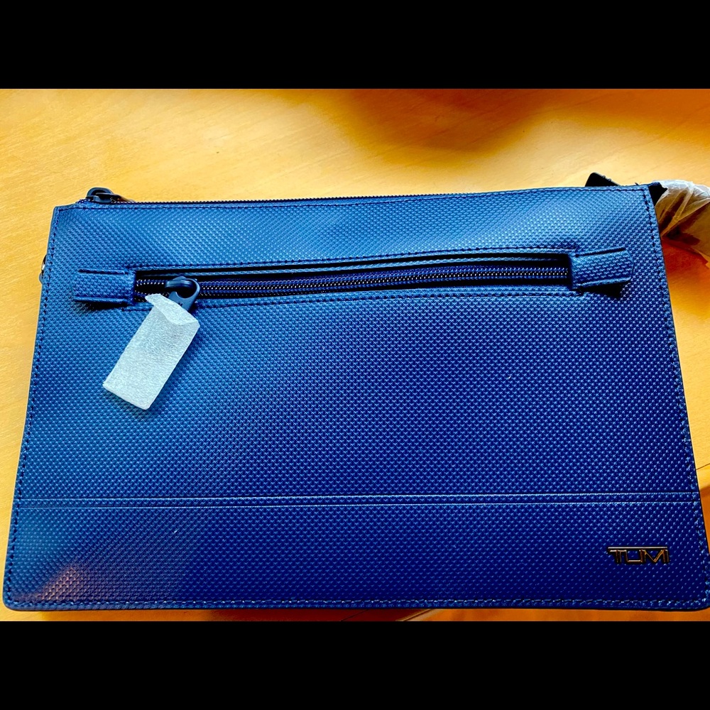 TUMI clutch, has a strap included